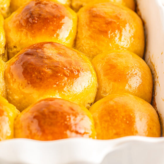 Buttered hawaiian rolls in a dish.