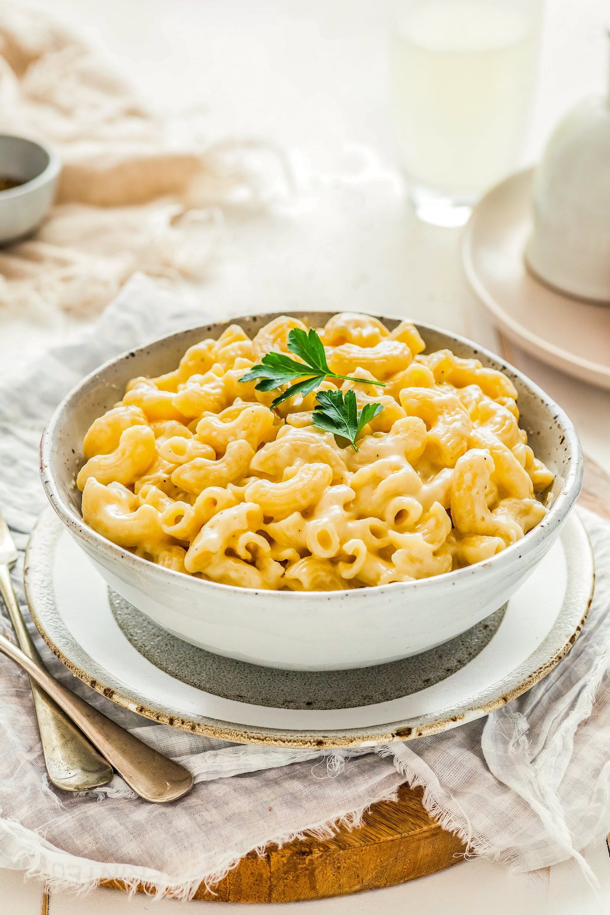This easy, one-pot homemade mac and cheese recipe is made extra creamy with three types of cheese! Bonus: It's ready in under 20 minutes. A small white bowl is filled with creamy, rich macaroni and cheese. It's garnished with fresh herbs.