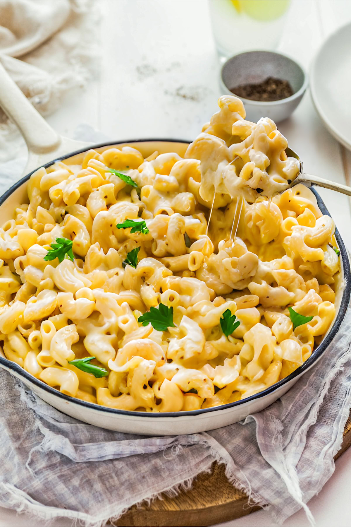 This easy, one-pot homemade mac and cheese recipe is made extra creamy with three types of cheese! Bonus: It's ready in under 20 minutes. A spoon is lifting a cheesy bite of macaroni from a full skillet.