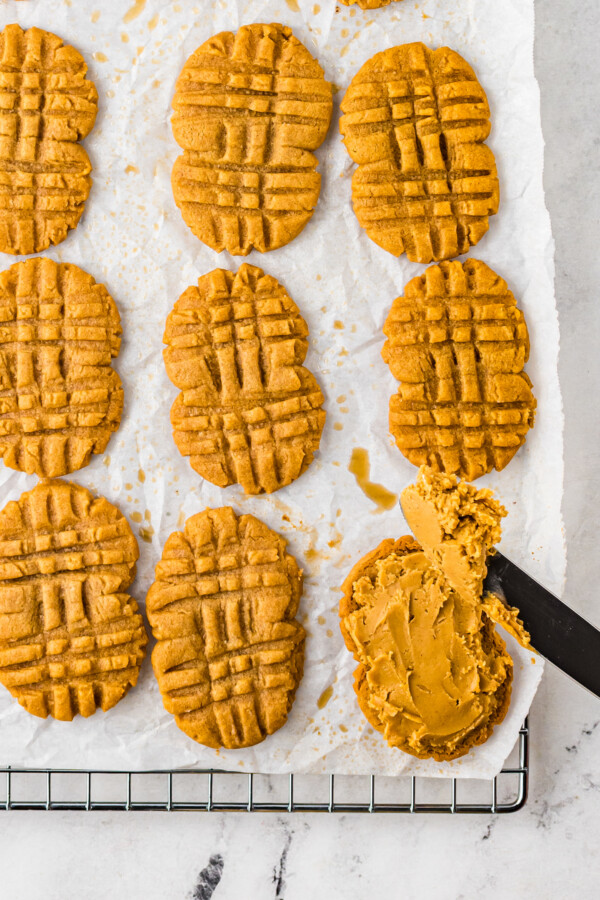 A pan of Nutter Butter cookies. One is being frosted with filling mixture.