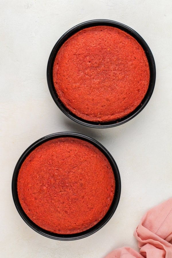 With a soft, tender crumb, this Homemade Strawberry Cake is made entirely from scratch with fresh berries and a creamy strawberry frosting! Two baked cake layers presented in baking pans.