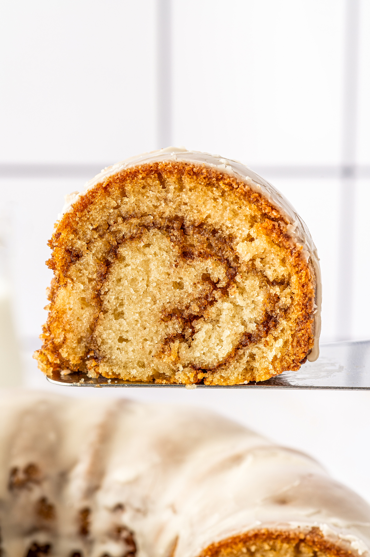 Honey Bun Cake is a spin on classic honey buns. You'll love this tender and moist, cinnamon-swirled bundt cake topped with a sugary glaze. A slice of cake from the side, showing swirls of cinnamon.