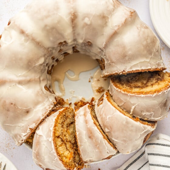 Landscape shot of cake on a table with cinnamon sticks, milk, and a cloth napkin.