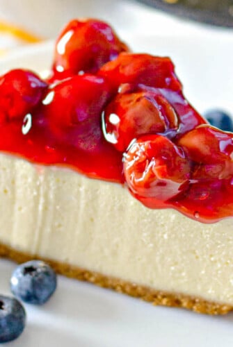 Up close image of a slice of cheesecake with cherries.