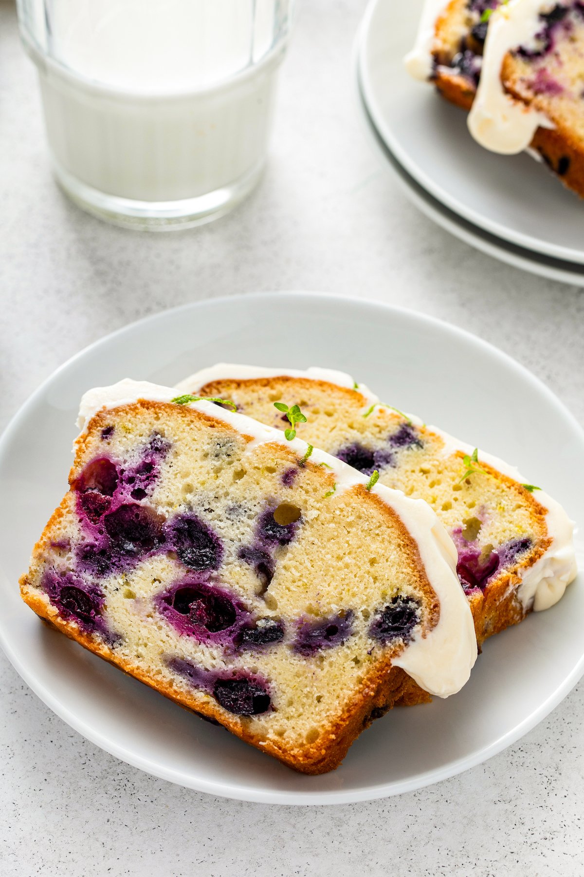 Slices of sweet and moist cream cheese pound cake with blueberries and lime zest on a plate.