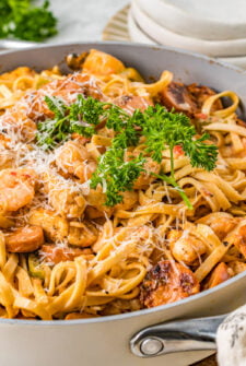 A large cooking pot of creamy pasta with shrimp, chicken, and sausage.