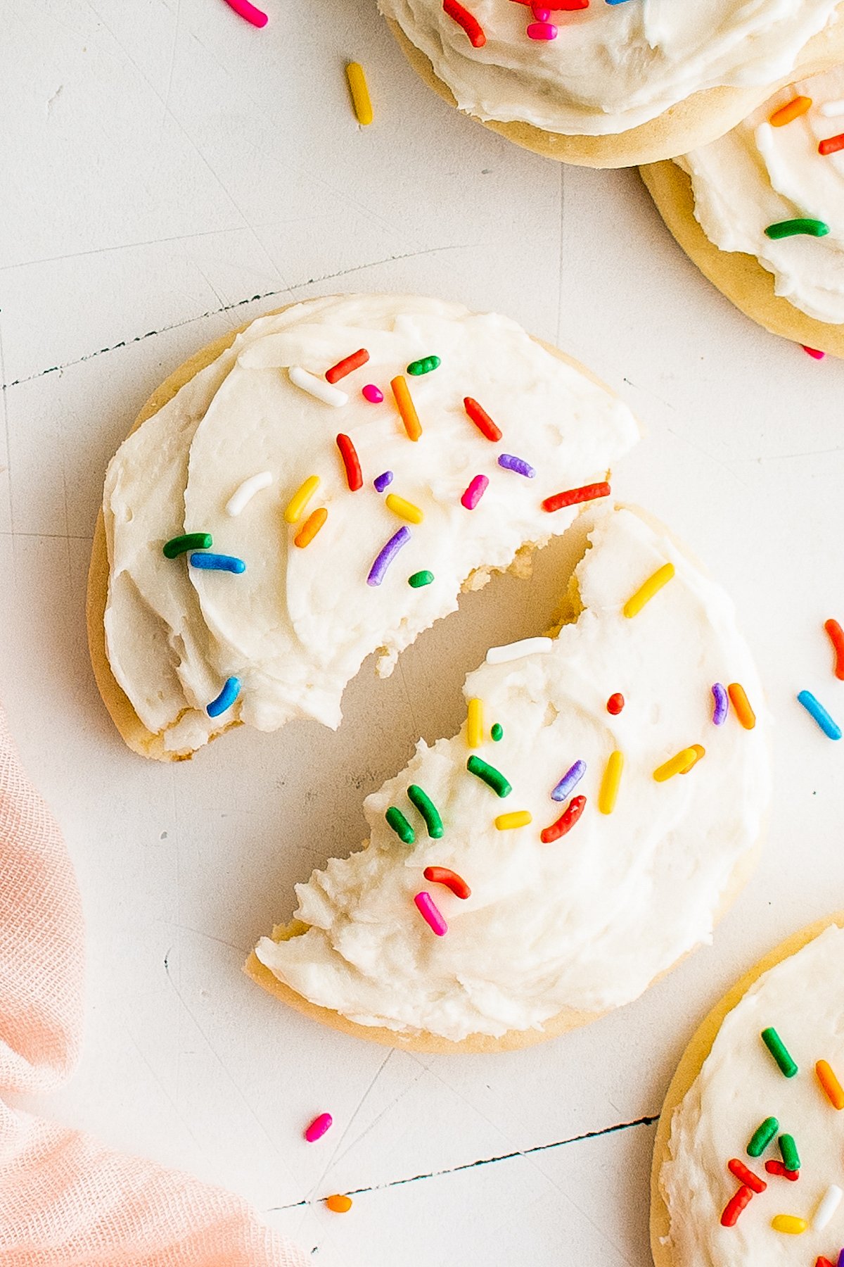 This copycat recipe for melt-in-your-mouth Lofthouse Cookies with homemade frosting are soft, thick and topped with fun sprinkles! A close-up shot of a Lofthouse cookie, broken in half.