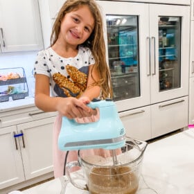 Lyla beating cake batter with an electric mixer.