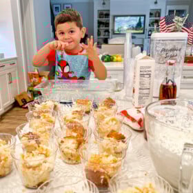 Milo helping make cups with coconut tres leche cake in them.