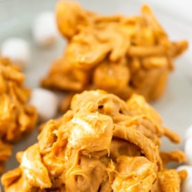 Three butterscotch haystacks on stacked plates with marshmallows.