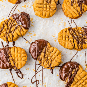 Peanut butter sandwich cookies dipped in chocolate on parchment paper.