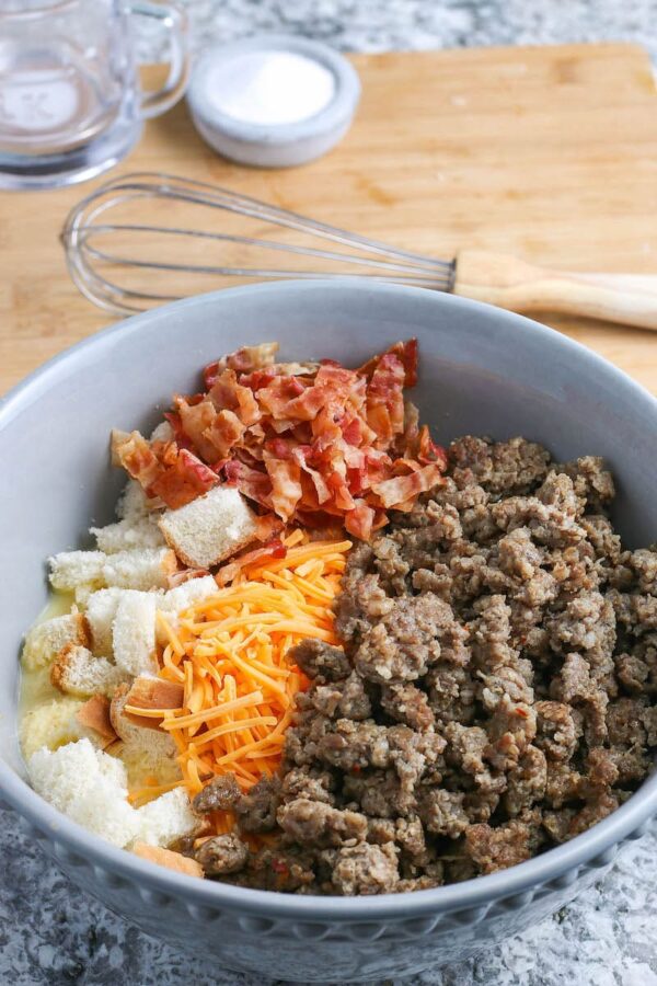 A blue bowl filled with sausage, bacon, bread and cheese.