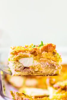 A serving of Overnight Breakfast Casserole with Ham being lifted out of a casserole dish with a spatula.