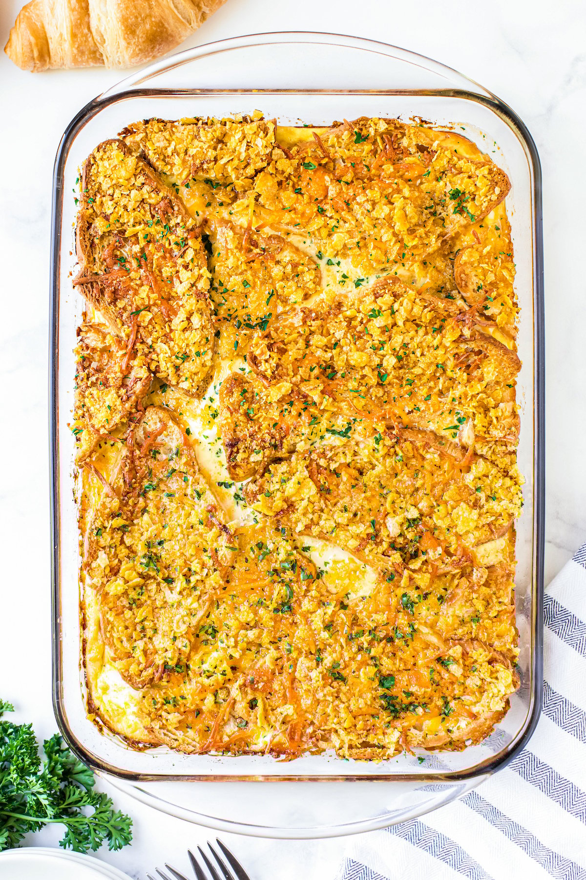 This overnight breakfast casserole with ham is made with flaky croissants, cream cheese and a crispy, buttery cornflake topping for crunch! Overnight Breakfast Casserole with Ham in a casserole dish baked with a buttery and crispy cornflake topping.