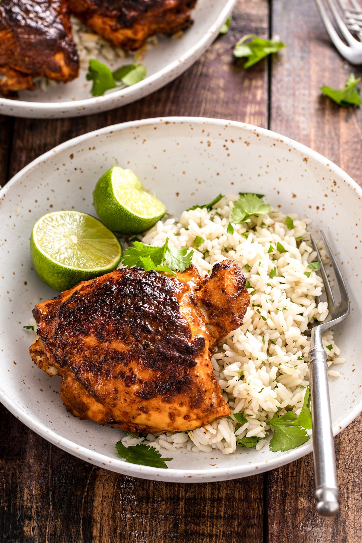This juicy Mexican pollo asado is tangy, sweet, and smoky. Loaded with orange juice and cumin, it's then grilled to tender perfection. Pollo asado served with rice, cilantro, and lime wedges.