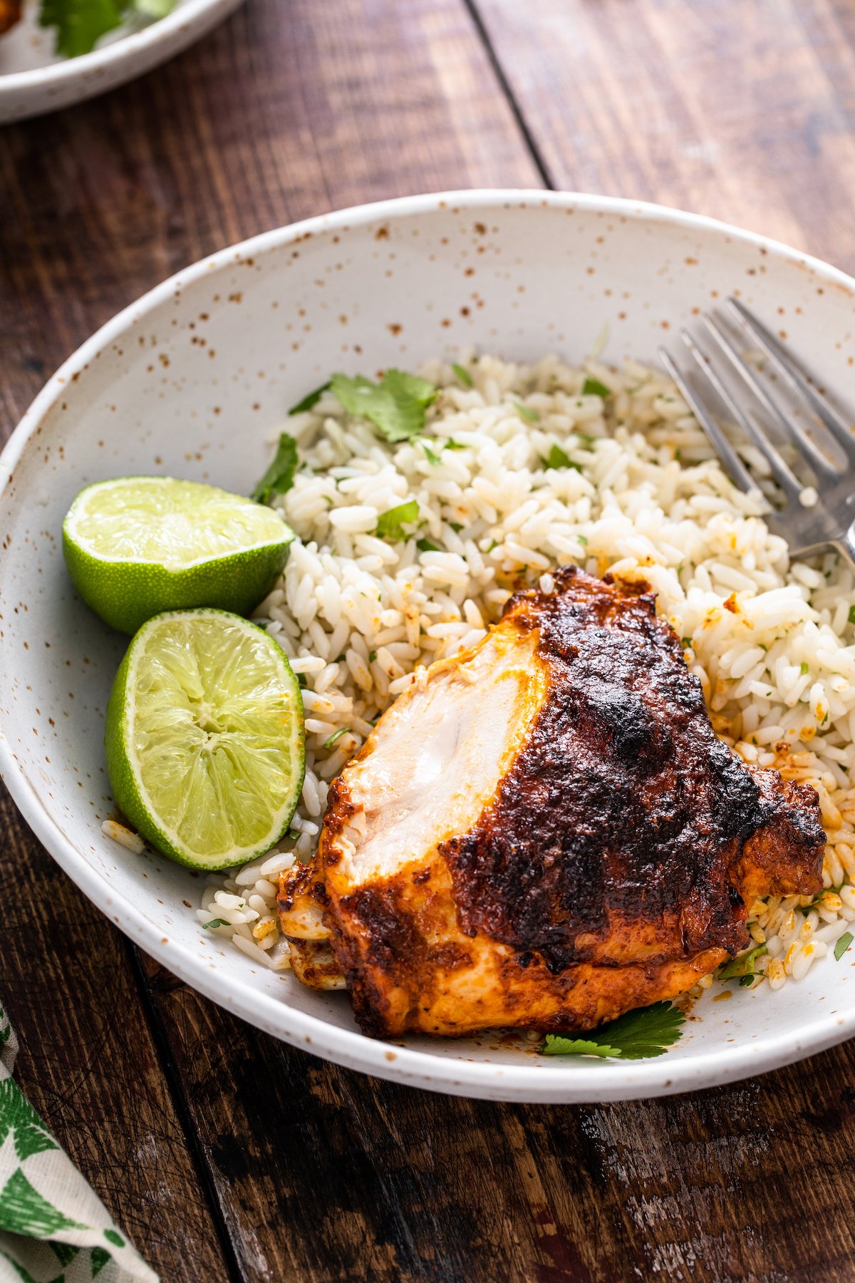 This juicy Mexican pollo asado is tangy, sweet, and smoky. Loaded with orange juice and cumin, it's then grilled to tender perfection. Sliced pollo asado served with rice, cilantro, and lime wedges.