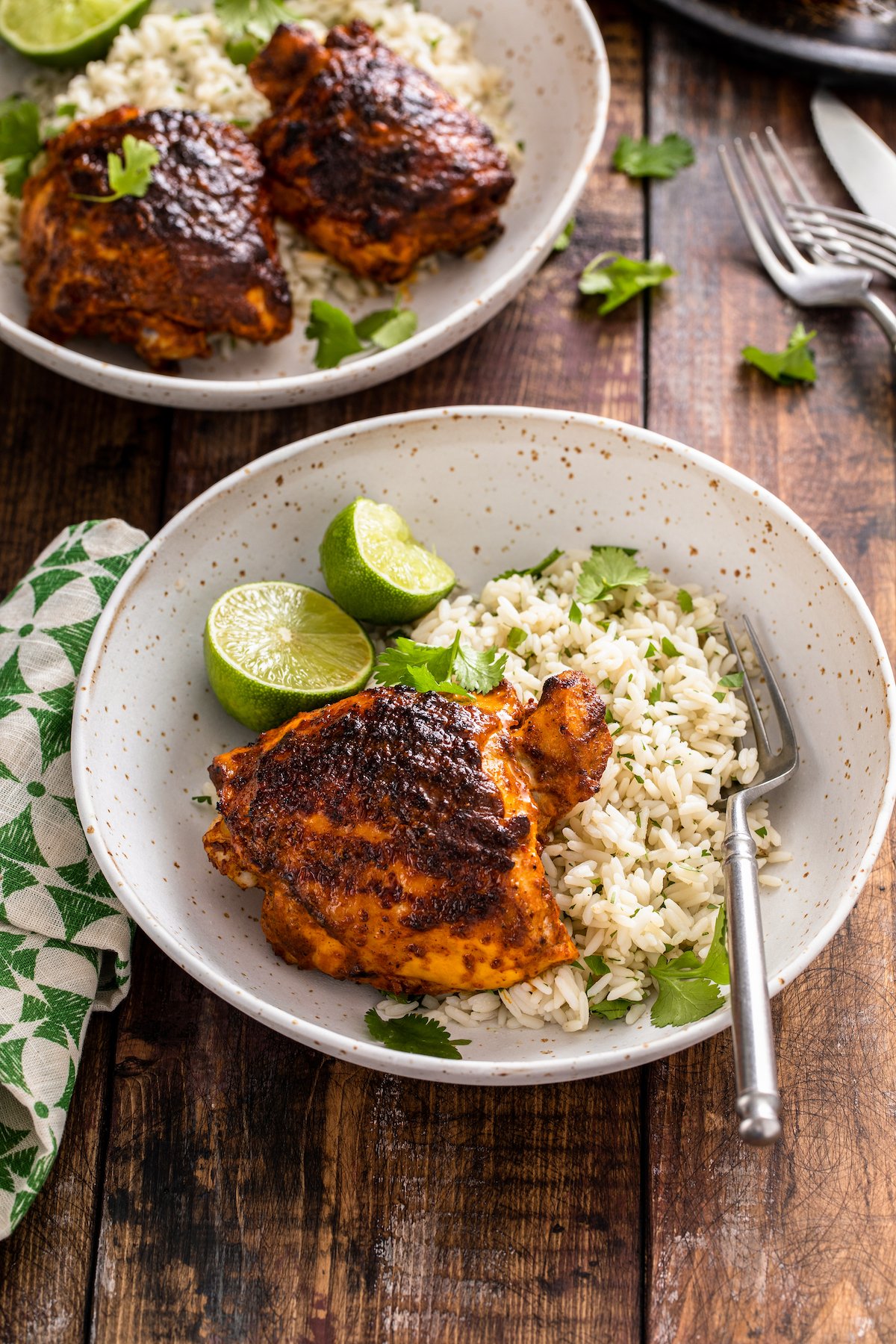 This juicy Mexican pollo asado is tangy, sweet, and smoky. Loaded with orange juice and cumin, it's then grilled to tender perfection. Pollo asado with rice, cilantro, and lime wedges.