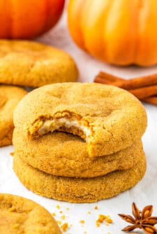 Stacked pumpkin cheesecake cookies. One has been bitten into.