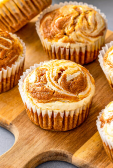 Pumpkin cream cheese muffins arranged on a board.