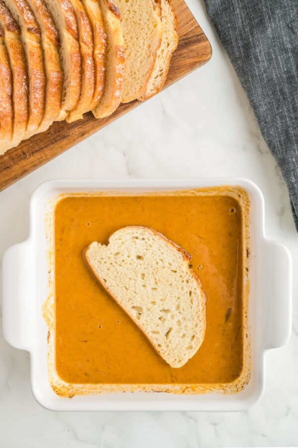Packed with pumpkin pie flavor, this quick and easy pumpkin French toast, served with maple syrup or powdered sugar, will disappear quickly! A slice of bread is being dipped into a baking dish filled with pumpkin mixture.