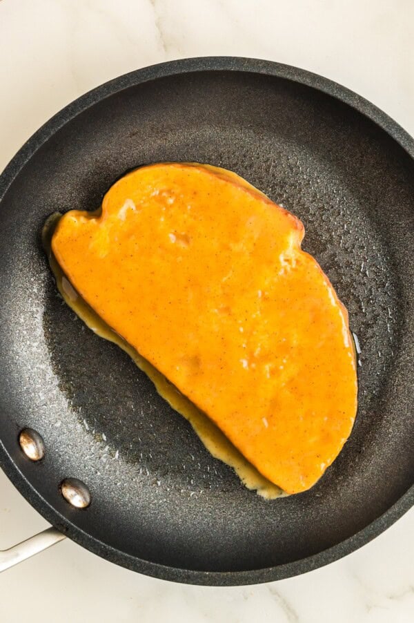 Packed with pumpkin pie flavor, this quick and easy pumpkin French toast, served with maple syrup or powdered sugar, will disappear quickly! A pumpkin battered slice of toast added to a skillet.