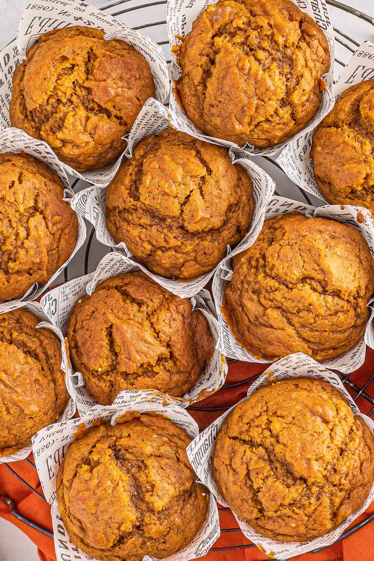 This bakery-style easy pumpkin muffin recipe creates moist and tender muffins made with a whole can of pumpkin and warm autumn spices! Large pumpkin muffins with liners on a cooling rack.