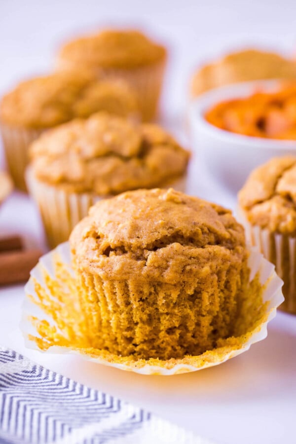 These Pumpkin Oatmeal Muffins are made easily in just one-bowl and are loaded with pumpkin flavor with a deliciously chewy consistency! Pumpkin oat muffin with the muffin liner being removed.