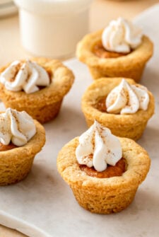 Mini pumpkin cookie cups garnished with whipped cream and pumpkin pie spice.