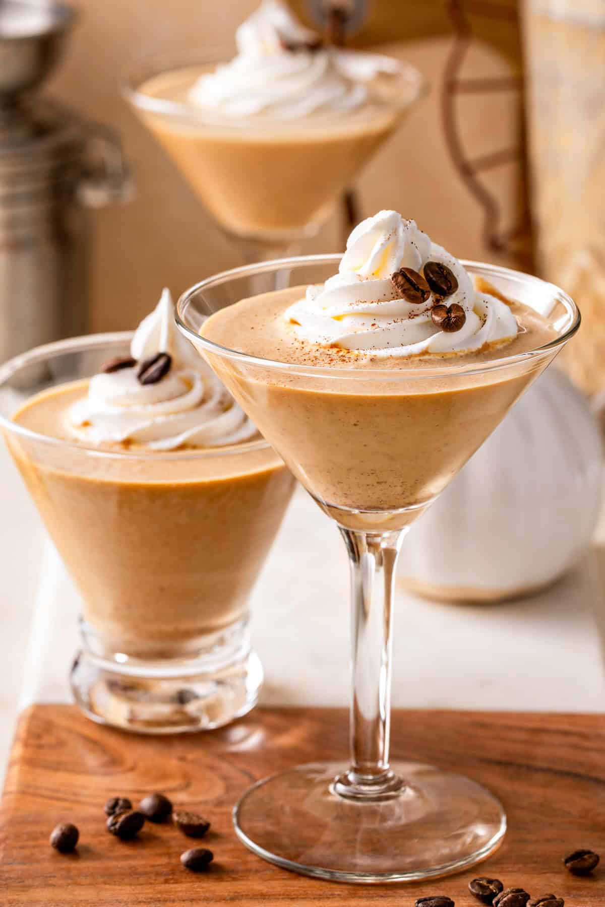Smooth, spiced, and perfectly creamy, this Pumpkin Espresso Martini fall in a glass. Made with real pumpkin, espresso, and RumChata! Three pumpkin spice espresso martini glasses are garnished with whipped cream, pumpkin spice, and coffee beans.