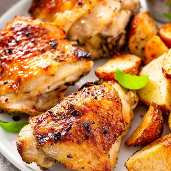 Perfectly baked chicken on a white plate with roasted potatoes.