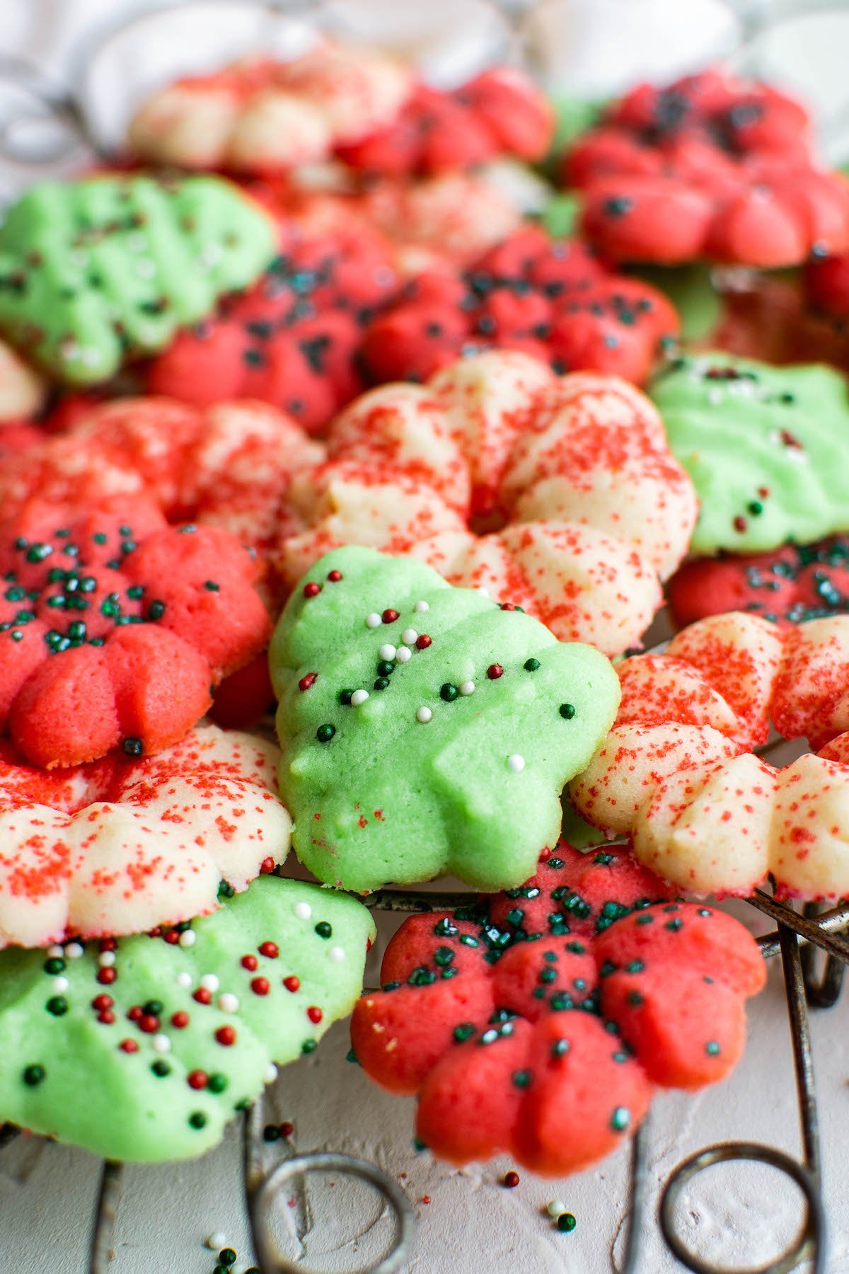 Buttery Spritz Cookies are perfect for Christmas! These red, white & green cookies are the sweet little treats that are totally irresistible. Spritz cookies on a cookie cooling rack!