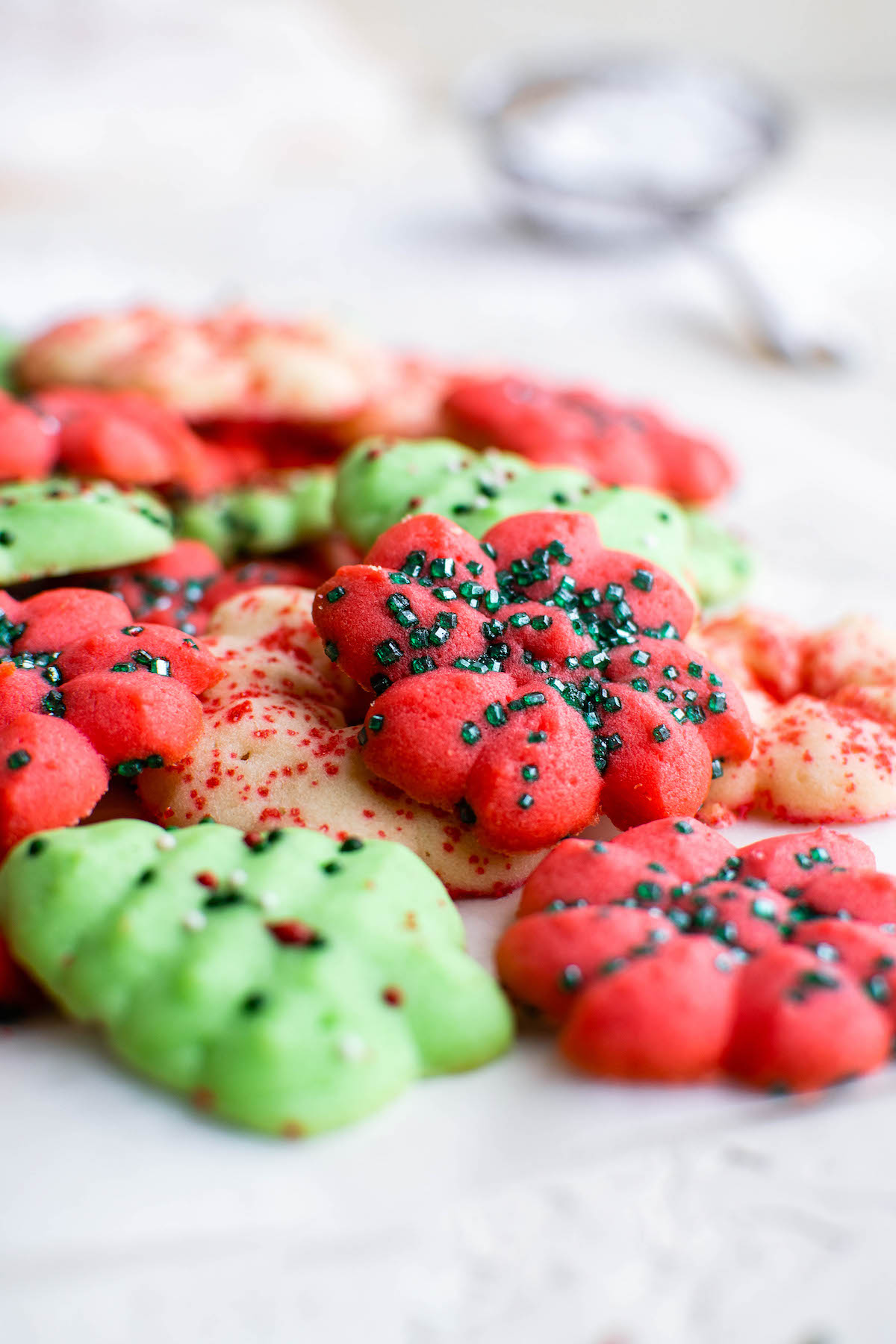 Buttery Spritz Cookies are perfect for Christmas! These red, white & green cookies are the sweet little treats that are totally irresistible. Spritz cookies arranged on a counter top.