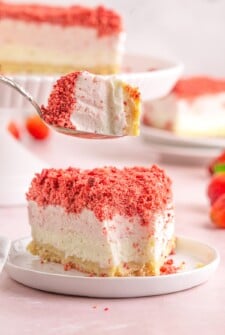 Lifting a bite from a slice of strawberry ice cream dessert.