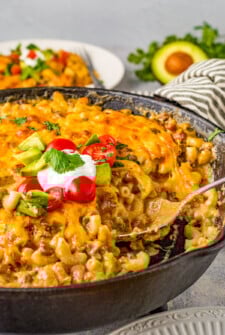 Taco mac and cheese in a skillet with a serving spoon.