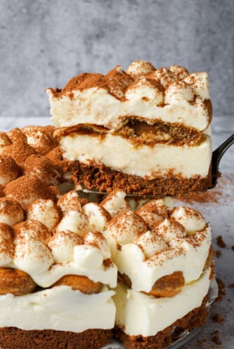A serving of layered cheesecake dessert being lifted on a cake server.