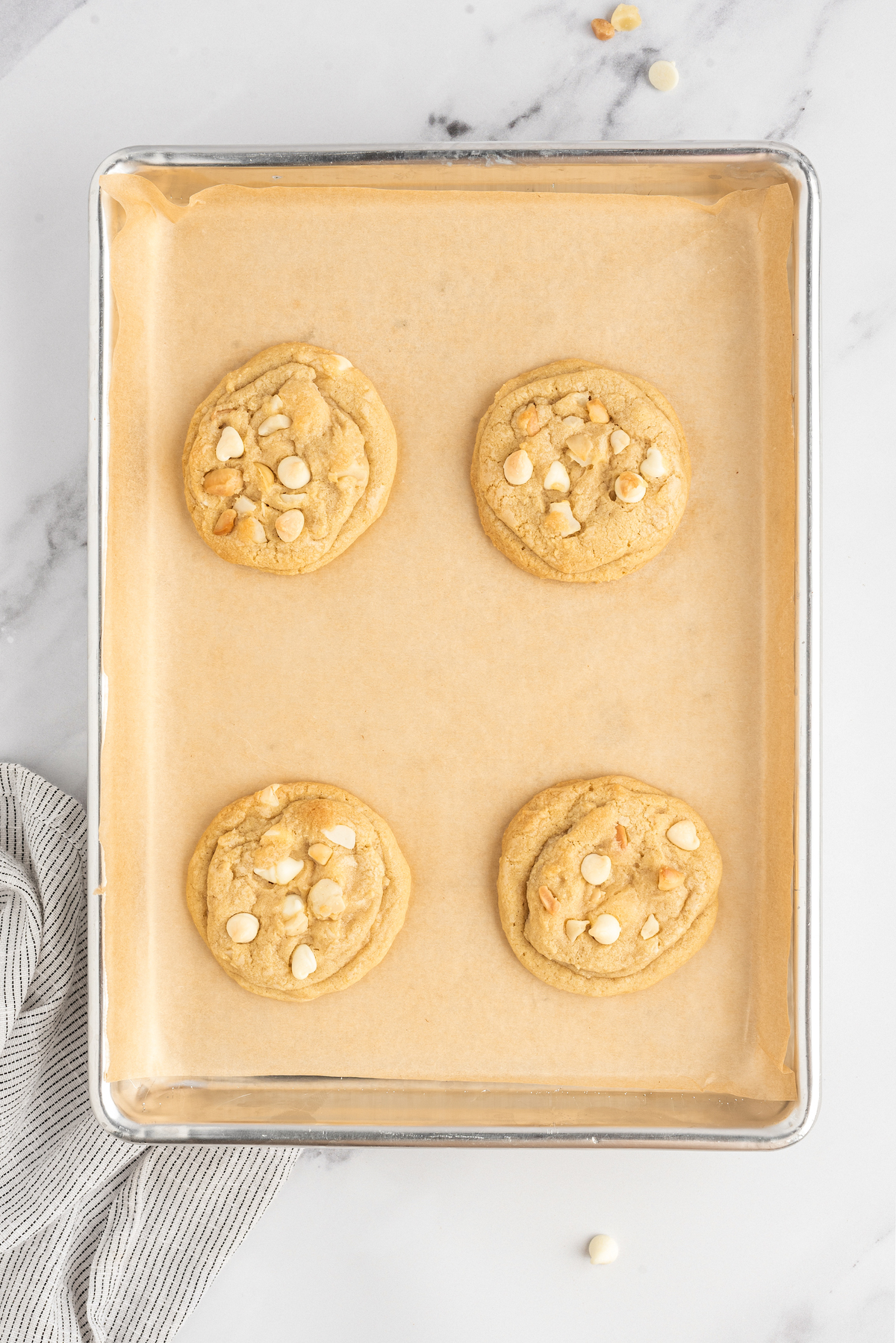 Salty-sweet White Chocolate Macadamia Nut Cookies have the perfect balance of chew and crunch. The best white chocolate chip cookies! Baked white chocolate cookies on a baking sheet.